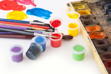 Different colored paints and brushes on a white background