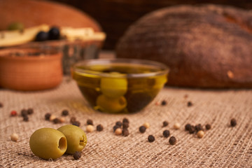 olive is on the table in background of bread, baguette and cheese. Selective focus