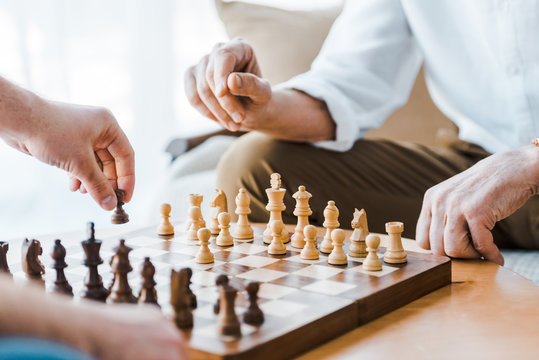 selective focus of wooden chess board with seniors playing chess at home - Powered by Adobe