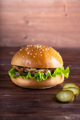 homemade hamburger with beef and cucumbers on wooden background