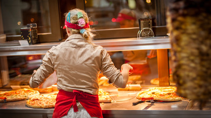 Woman worker selling pizza in fast food restaurant. Rear view