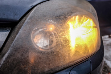 Car front headlights, scratched, dirty and opaque, blurred