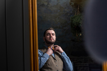 groom looking in mirror and touching bowtie