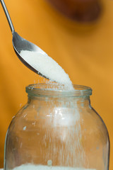 sugar poured into a jar with a steel spoon, close-up