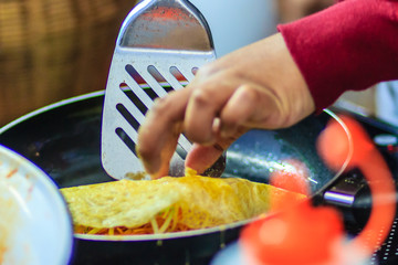 Close up hand of vendor during cooking for the original Thai Fried Noodle(Pad Mee Boran), stir-fried noodle with shrimp and egg commonly served as a street food popular in Thailand