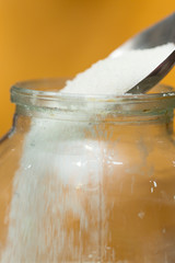 sugar poured into a jar with a steel spoon, close-up