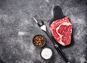 Raw marbled ribeye steak and spices