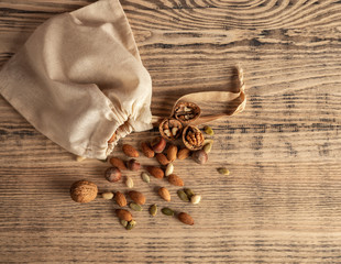 Almond nuts, hazelnuts, walnuts and sweet seeds in a burlap bag on a wooden background. Top view.
