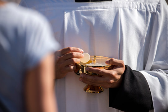 Catholic priest giving beliver a Holy Communion