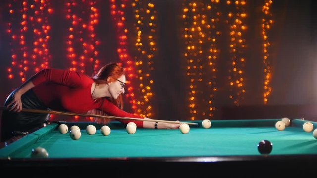 Concentrated ginger woman playing billiard in billiard club