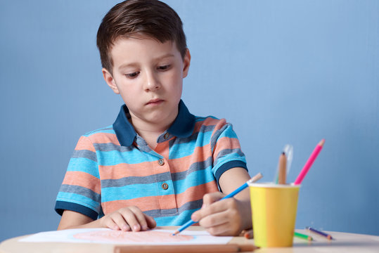 European boy spending time drawing with colorful pencils at home.