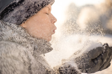 a beauty girl blowing on snow on the winter background.