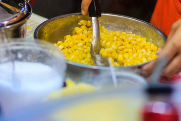 Close up hand of street vendor during cooking for mixed corn butter, sweet and simply Thai dessert.