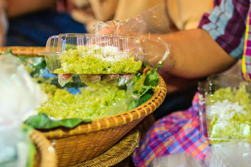 Thai vendor is selling shredded rice grain dessert to the customer at night market. Steamed shredded rice grain with coconut, This Thai desert is called 