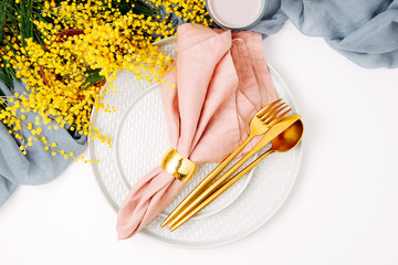 Festive table setting. Plates and cutlery with gray decorative textile and yellow flowers on white...