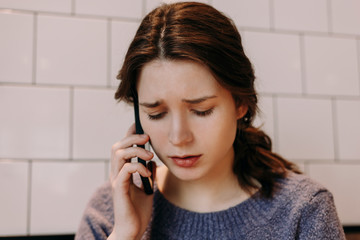 Worried young girl is talking on the phone. She looks very unhappy.