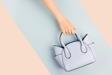 Fototapeta Female hands holds handbag on blue background . Flat lay, top view. Spring fashion concept in pastel colored obraz