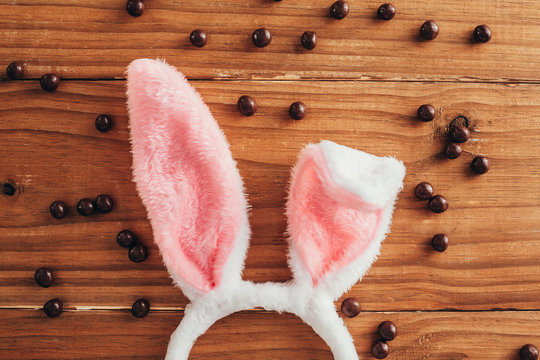 Easter concept. Rabbit ears between chocolate balls on wooden background