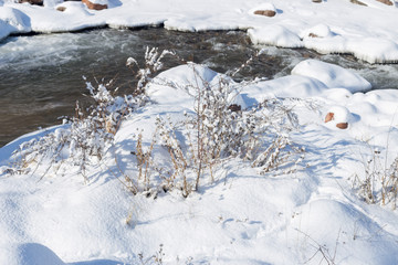 smooth movement of wild water in a river in winter with snow and ice on rocks and stones in beautiful nature