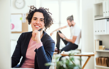 A portrait of young businesswoman sitting in a modern office.