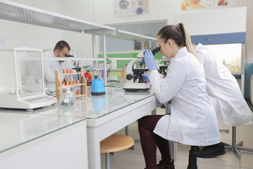 Group of young Laboratory scientists working at lab with test tubes and microscope, test or research in clinical laboratory.Science, chemistry, biology, medicine and people concept.