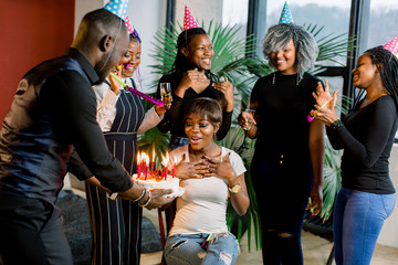 Friends presenting a birthday cake to the african girl