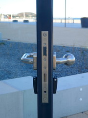 Open glass door, details of the side view. Close-up of door handle, doorknob and door lock,