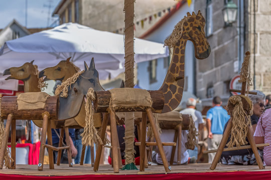View of archaic wooden carousel, medieval fair of Canas de Senhorim, people and buildings as background