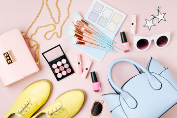 Flat lay of female fashion accessories, makeup products and handbag on pastel color background....