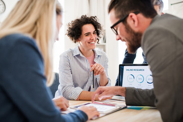 Group of young businesspeople with laptop working together in a modern office.