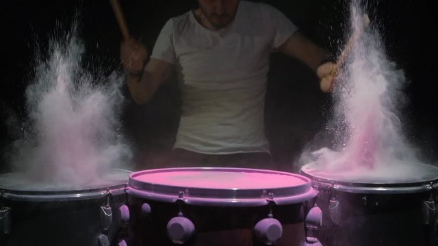 Red holi powder bounces off drum in shockwave pattern, slow motion. black background.