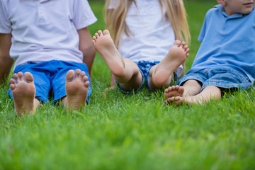 Happy children show their feet close up in the park. Barefoot on the green grass