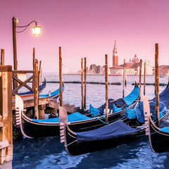Fototapeta na wymiar Majestic Gondolas in Venice at the sunset. Panoramic view of the San Giorgio Maggiore church from San Marco square. Travel and Vacation in Italy concept