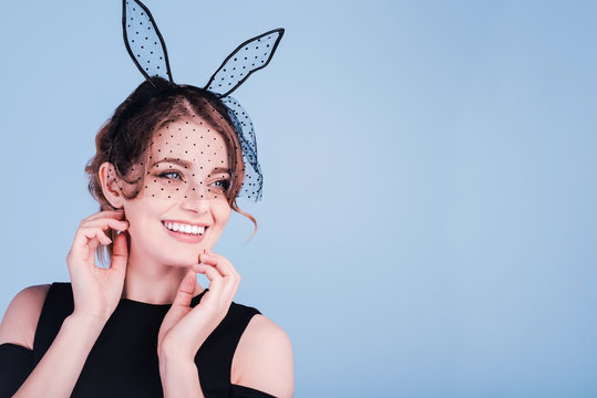 Beautiful happy and smiling young woman as easter bunny with rabbit ears on blue background.