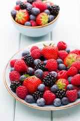 Fresh berry salad on blue dishes. Vintage wooden background.