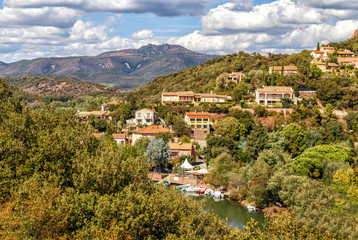 Fototapeta na wymiar A village in the mountains in a clear summer sunny day, red rocks of Esterel massif, Provence, Southern France. Holidays in France.