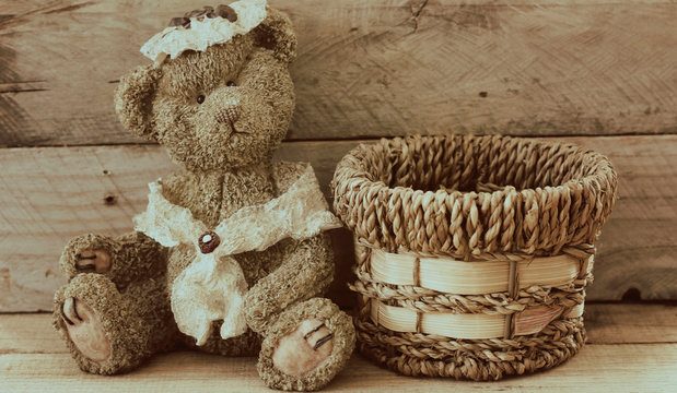 vintage bear sitting next to a woven basket on a wood background with writing space perfect for greeting card