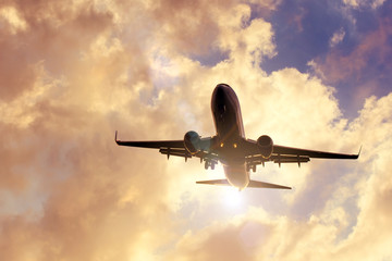 Evening sky with razravynnymi beautiful clouds of warm colors and airplane approaching the landing.