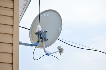 Satellite dish antenna hanging on the wall of the house