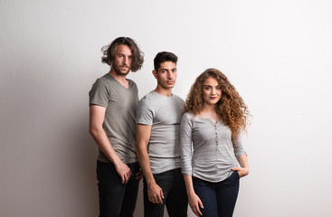 Obraz premium Portrait of young girl with two boy friends standing in a studio.