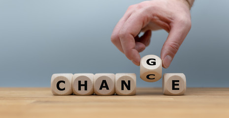 Hand flips a dice and changes the word "change" to "chance"