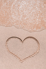 Ocean wave and heart drawn on the sand