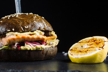 Delicious salmon burger, black dough buns sprinkled with sesame.