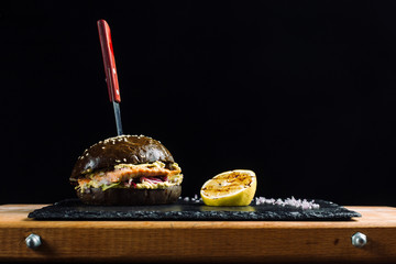 Delicious salmon burger, black dough buns sprinkled with sesame.