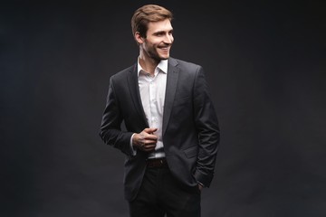 Portrait of a handsome young businessman dressed in suit isolated over gray background.