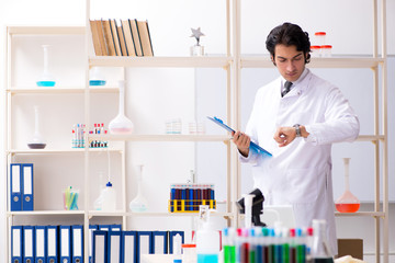 Young handsome chemist working in the lab