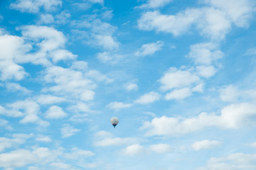 blauer Himmel mit kleinen Schäfchenwolken und Heißluftballon