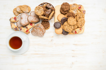 Flat lay of chocolate chip cookies and a cup of tea on a white wooden table
