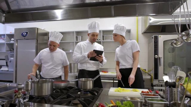 busy cooks and kitchen chef consulting with tablet 