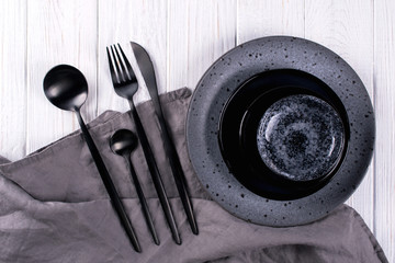 Set of porcelain handcraft  grey and black plates and  bowls cutlery set, linen napkin on a white...